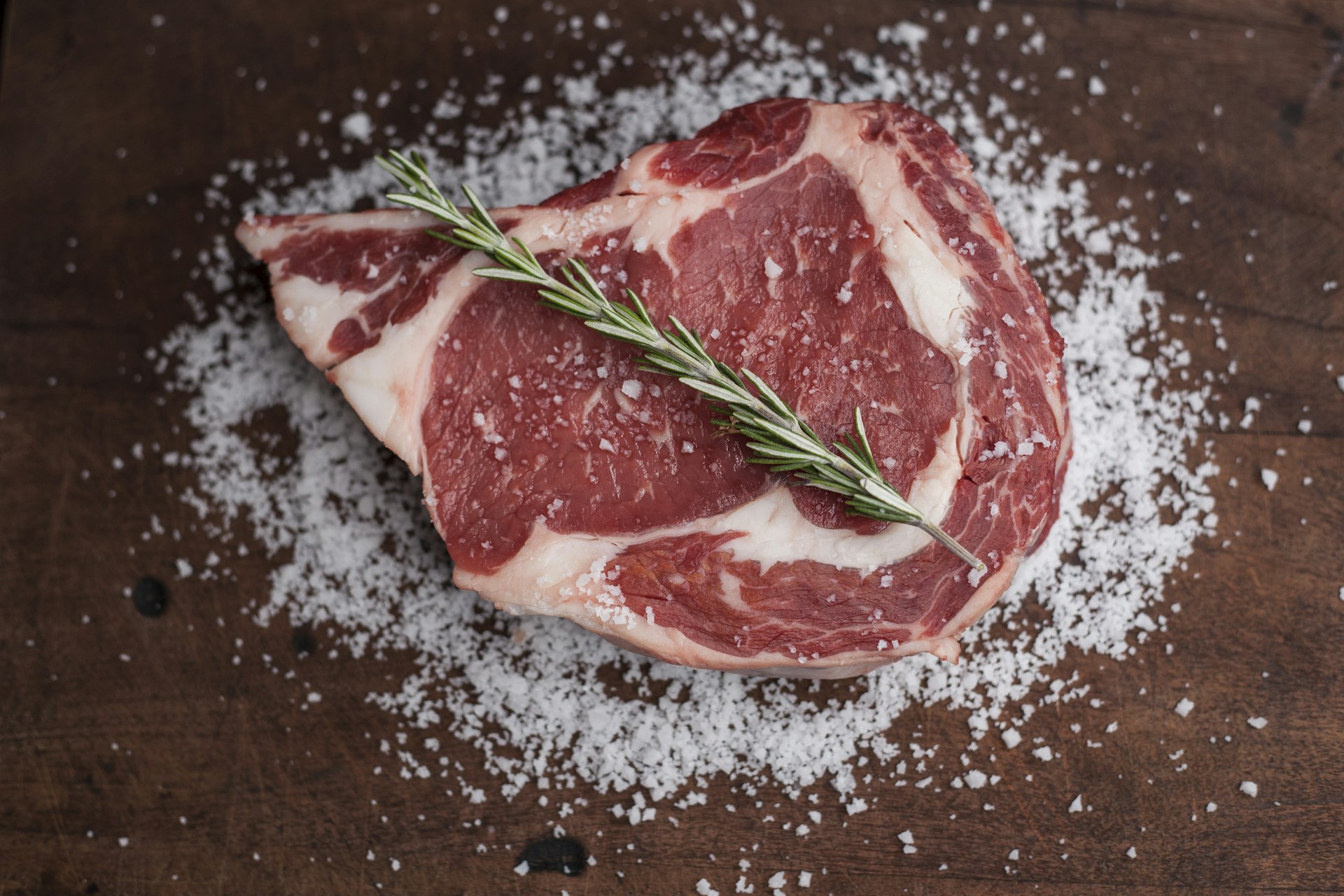 Gerijpte ribeye met rozemarijn en zeezout op een donkere plank